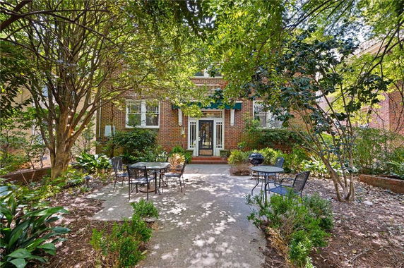Front view of a brick house with a patio and outdoor seating.