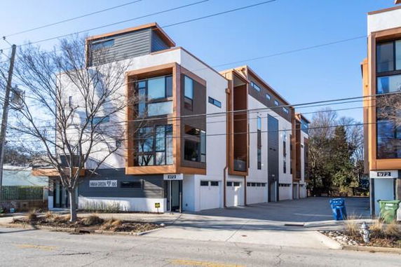 Front view of a modern multi-story building with large windows and garage spaces.