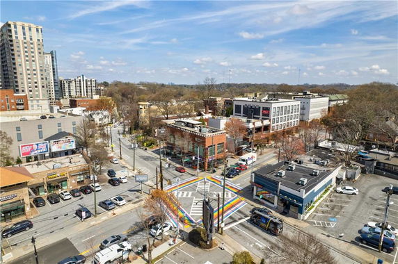 Aerial view of an urban street intersection with buildings, parking areas, and a rainbow crosswalk.