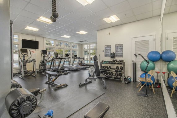 Indoor gym area with exercise equipment and weights.