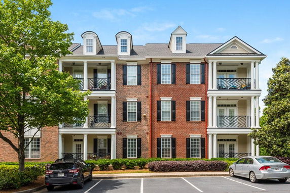 Front view of a three-story brick building with balconies and white columns.