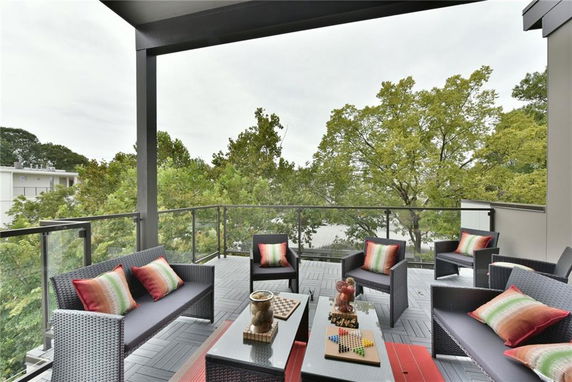 Outdoor balcony with modern furniture and view of trees.