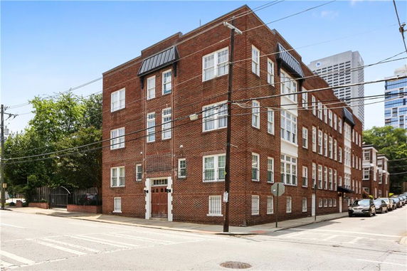 Front view of a multi-story brick apartment building on a corner lot.