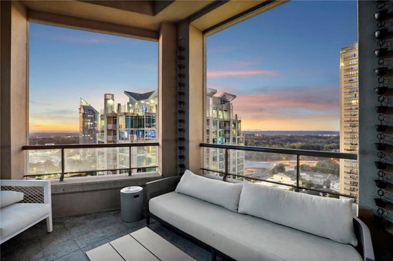 High-rise outdoor balcony with panoramic view of cityscape at sunset.