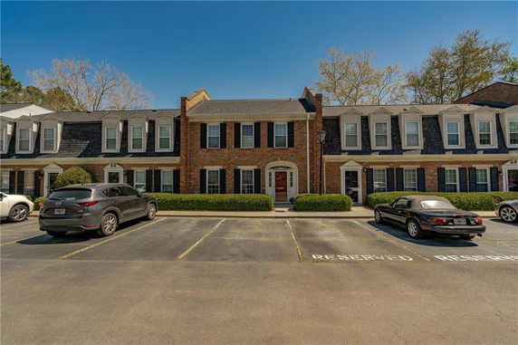 Front view of a two-story brick townhouse with a parking area in front.