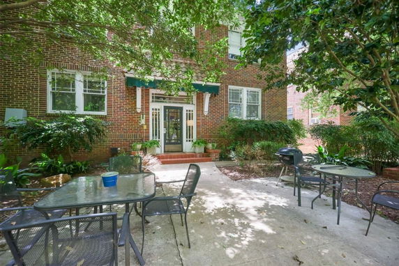 Front view of a brick building with a patio area and outdoor furniture.