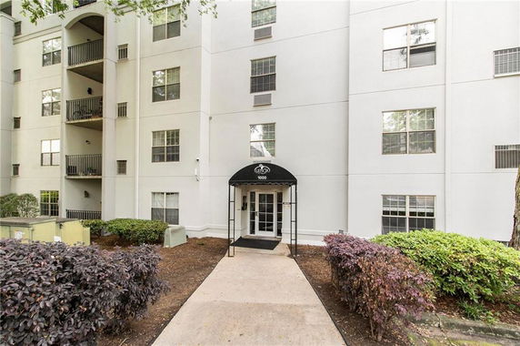 Front view of a multi-story building with balconies and an entrance canopy.