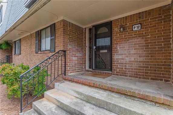 Front view of a brick house with steps leading to the entrance.