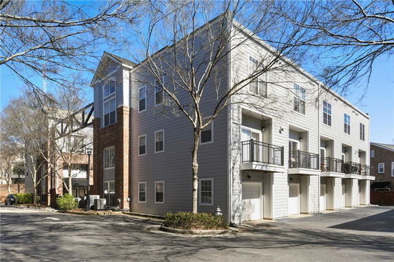Front view of a multi-story building with garages and balconies.