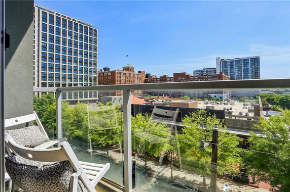 View from a building balcony overlooking cityscape with modern and historic buildings.