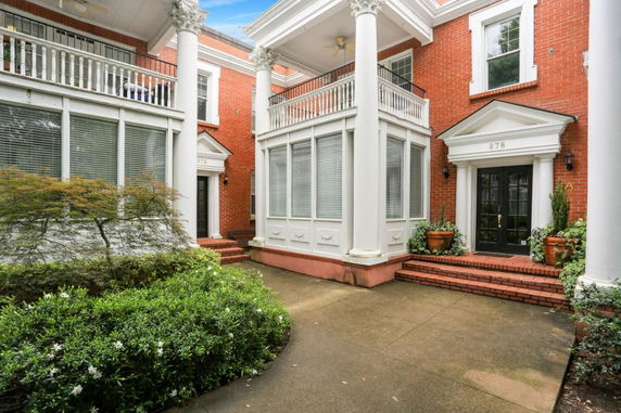 Front view of a two-story brick house with large white columns and a balcony.