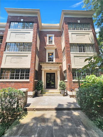 Front view of a multi-story brick building with large windows and a central entrance.