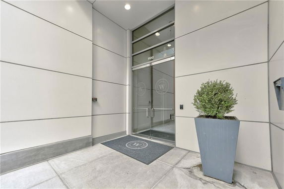Entrance of a modern building with glass doors and a potted plant.