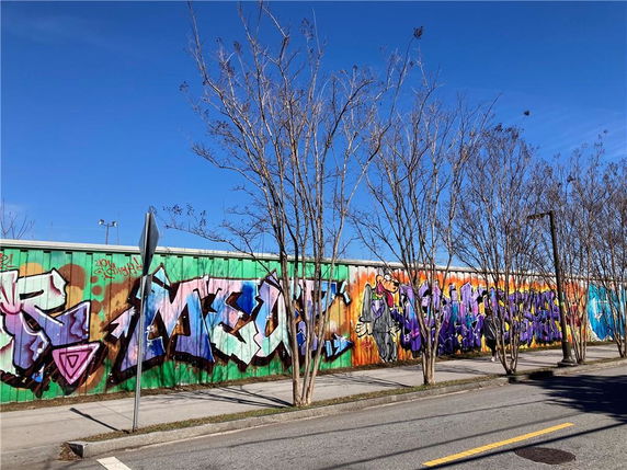 Building facade with colorful graffiti art on a metal wall next to a street.
