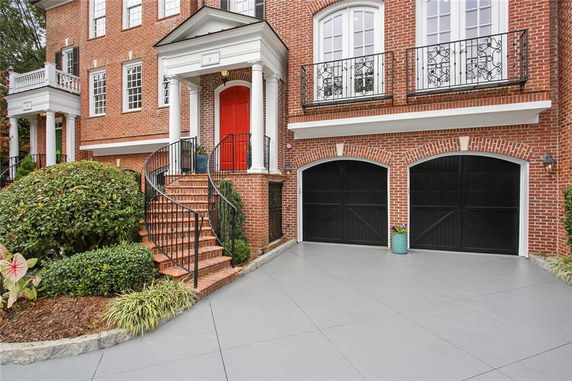 Front view of a brick house with a red door and double garage.