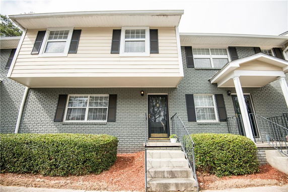 Front view of a two-story townhouse with a brick exterior and stairs leading to the entrance.
