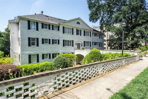 Front view of a two-story residential building with black shutters and a small walkway.