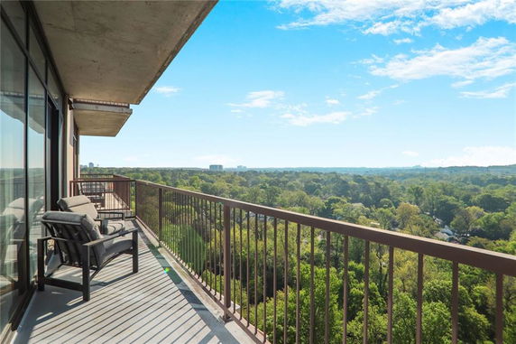 Balcony with outdoor seating offering a panoramic view of a forested area.