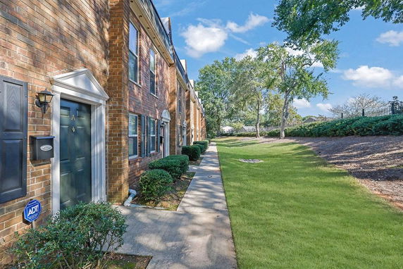 Front view of a brick row house with a pathway and lawn.