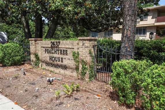 Front view of Peachtree House Condominium with a brick sign and gate.