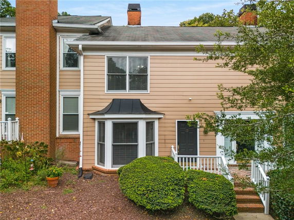 Front view of a two-story house with a bay window and a black front door.