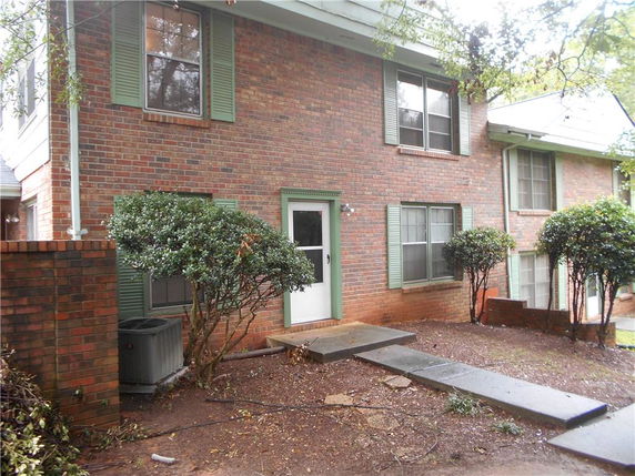 Front view of a two-story brick house with green shutters and a side entrance.