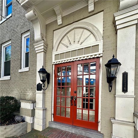 Front view of a building entrance with red double doors and decorative arch.