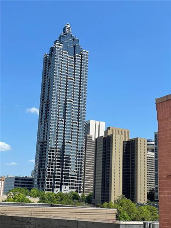 Front view of a tall skyscraper with a spire, surrounded by other high-rise buildings.