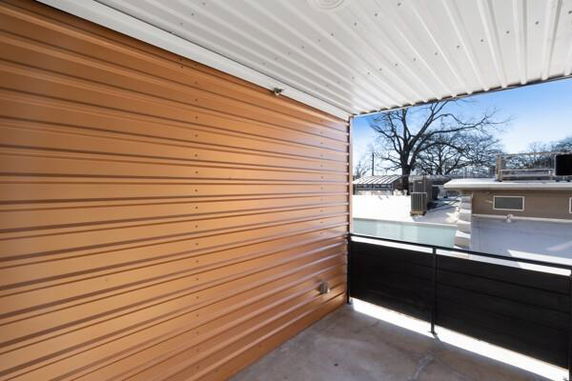 View of a rooftop area with a metal railing and a brown paneled wall.
