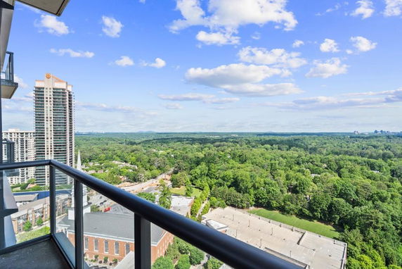 Panoramic view from a high-rise balcony overlooking a landscape of trees and buildings.