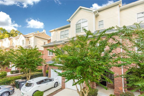 Front view of a multi-story townhouse with brick and siding exterior.