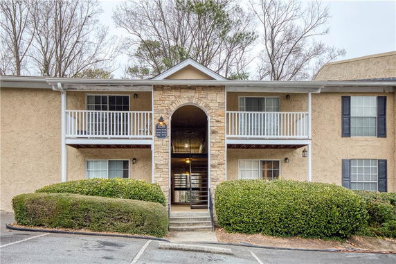 Front view of a two-story residential building with a central archway and balconies.