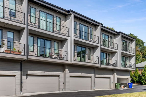 Front view of a multi-story residential building with balconies and garages.