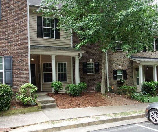 Front view of a two-story townhouse with brick and siding exterior and a small porch.