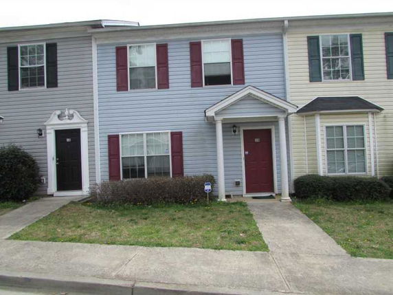 Front view of a two-story townhouse with blue siding and red shutters.