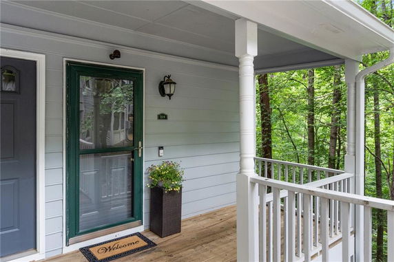 Front porch view with a green door and welcome mat.