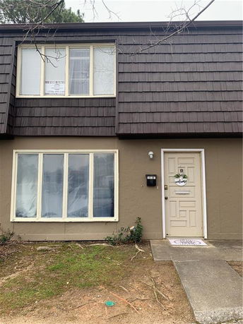 Front view of a two-story house with a brown exterior and a single entrance door.