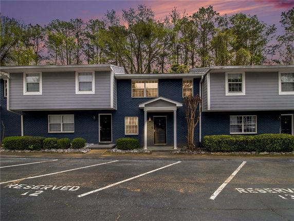 Front view of a two-story building with a central entrance and parking spaces.