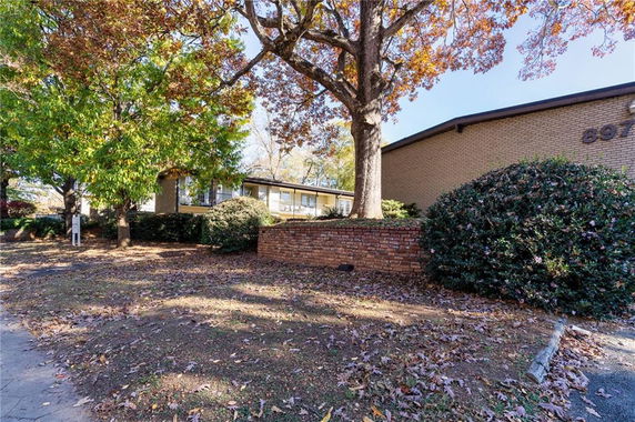 Front view of a brick building with a flat roof and adjacent trees.