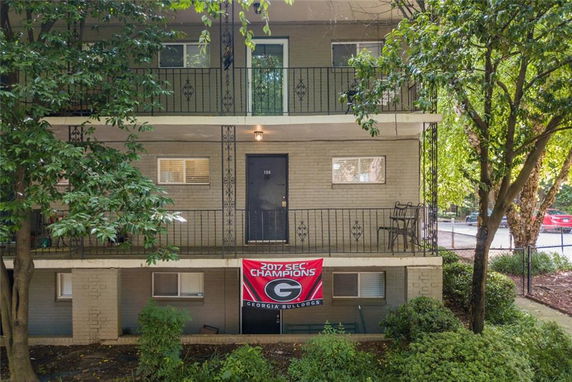 Front view of a two-story apartment building with balconies and a banner on the lower level.