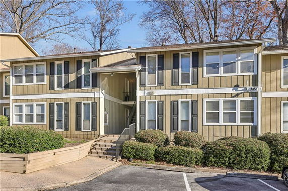 Front view of a two-story residential building with beige siding and dark shutters.
