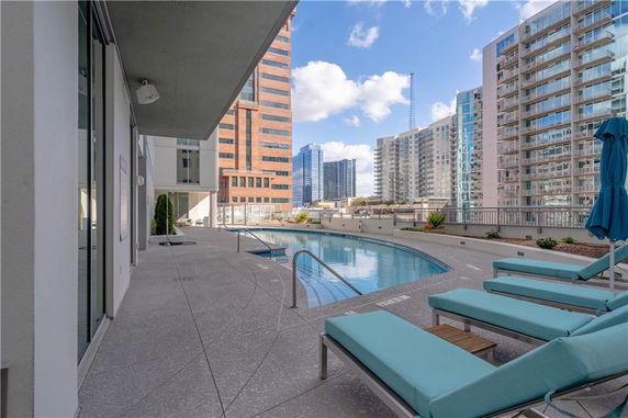 Outdoor swimming pool area on a high-rise building with surrounding city skyline views.