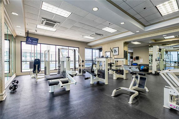 Interior view of a gym with various exercise equipment and large windows.