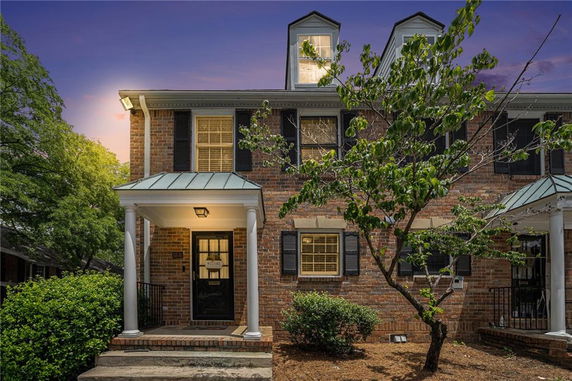 Front view of a brick house with two dormer windows and a covered porch.