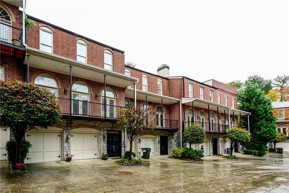 Front view of a multi-story brick townhouse with balconies and garages.