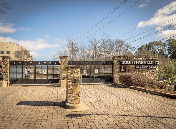 Front view of entrance to a residential complex with stone walls and metal gates.