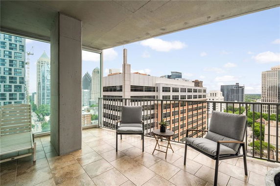 Wide angle view of cityscape from a high-rise balcony with outdoor chairs.