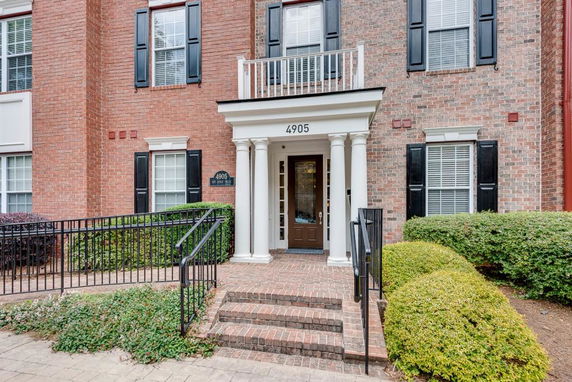 Front view of a brick building entrance with white columns.
