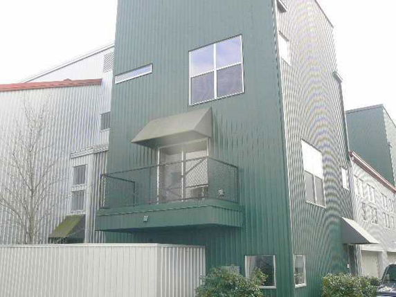 Front view of a multi-story building with a green exterior and a small balcony.