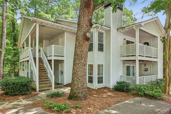 Front view of a two-story house with a wraparound balcony and exterior staircase.